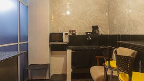 A compact kitchen with a microwave, coffee maker, and a small table. - Barra da Tijuca Guest Houses (Rio de Janeiro)
