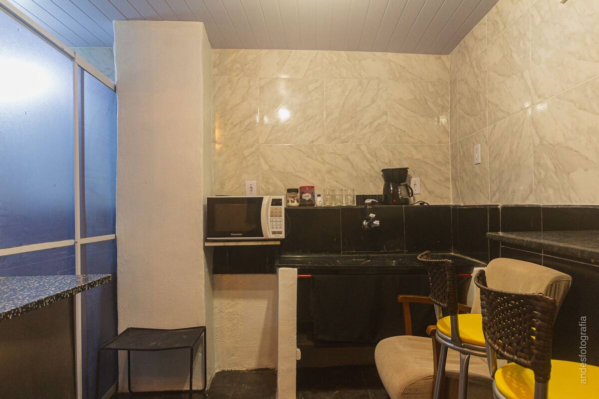 Une cuisine compacte équipée d’un four à micro-ondes, d’une machine à café et d’une petite table.
