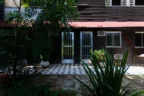 A house with a tiled patio, a red roof, and a garden with potted plants.