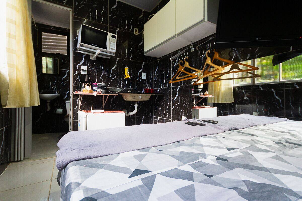 Une chambre moderne avec une couvre-lit à motifs géométriques, un téléviseur intégré, un four à micro-ondes et un lavabo dans la salle de bain attenante.