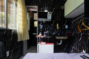 Et lille hotelværelse med tekøkken, mikroovn, vask og seng.