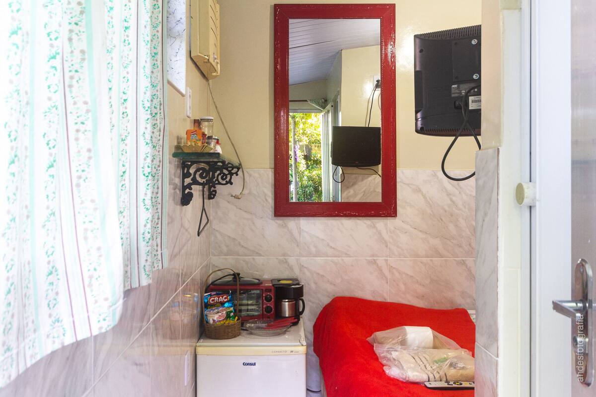 Une chambre de taille réduite, équipée d’un petit lit, d’une machine à café et d’un réfrigérateur.