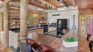 Una cocina rústica con vigas de madera, una isla central y un comedor.