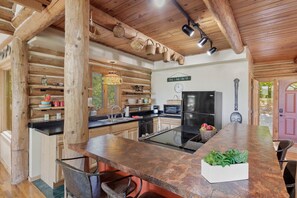A rustic kitchen with wooden beams, a central island, and a dining area.