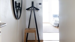 A narrow hallway with a wooden stool, a black tripod, and a wall-mounted mirror. - 2ndhomes Central 1BR Apartment w Balcony (Helsinki)