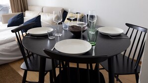 A dining table set with plates, glasses, and cutlery in a room with a bed and a sofa. - 2ndhomes Central 1BR Apartment w Balcony (Helsinki)