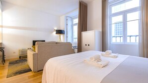 A hotel room with a bed, a sofa, a desk, a lamp, and a wardrobe. - Central Downtown Apartment by LovelyStay (Lisboa)