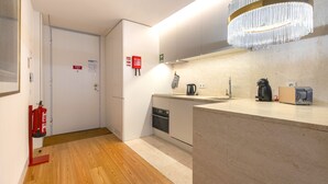 A modern kitchen with a built-in oven, a coffee machine, and a toaster. There is a fire extinguisher mounted on the wall and a small sink. - Central Downtown Apartment by LovelyStay (Lisboa)