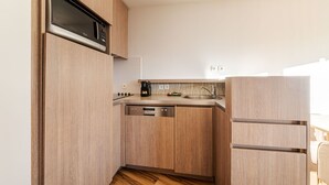 Eine kleine Küche mit Holzausstattung, einer integrierten Mikrowelle, einem Geschirrspüler und einem Kühlschrank.