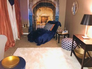 A cozy room with a dark blue sofa, a small table with a chessboard, and a lamp.