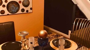 Un comedor con una mesa dispuesta para cuatro, una pared decorativa con motivos circulares y una escalera de diseño geométrico.