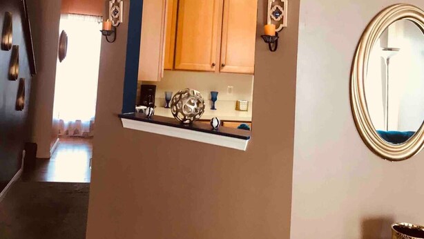 Un pasillo con un espejo, una zona de cocina y una puerta que da a otra habitación.