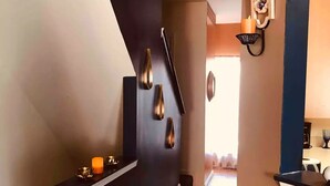 Un pasillo con una pared de acento oscura, un zócalo blanco y un pequeño estante con adornos.
