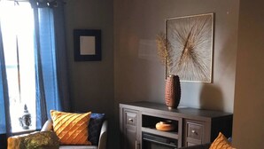 Una sala de estar con chimenea, una mesa de centro con una escultura y dos sofás con cojines estampados.