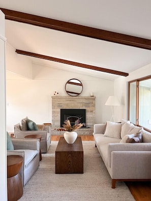 Un salon moderne avec une cheminée, deux canapés, une table basse et un plancher en bois.