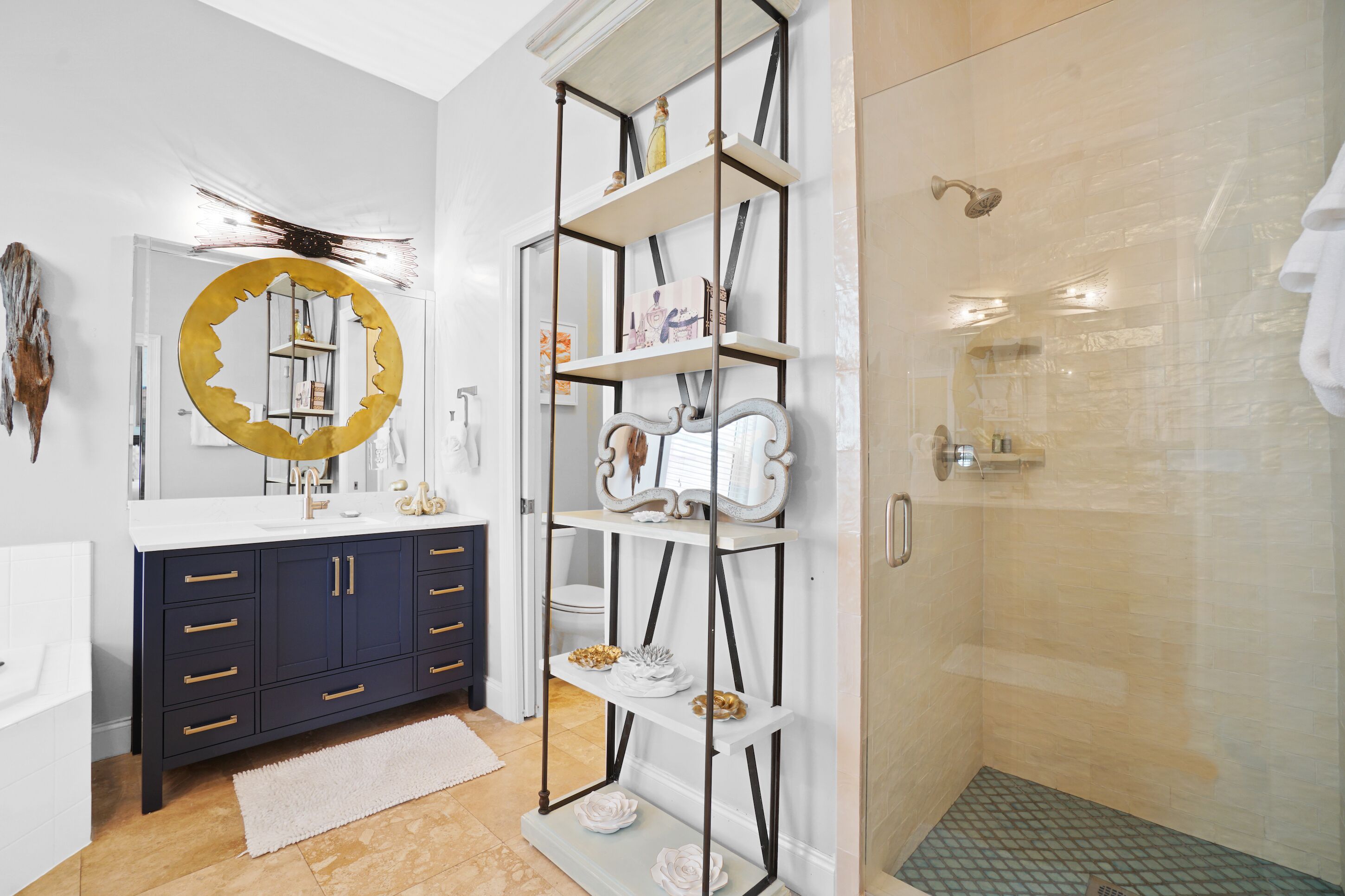 A modern bathroom with a vanity, a large mirror, a shower, and a decorative shelf.