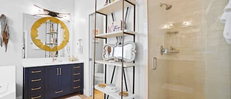 A modern bathroom with a vanity, a large mirror, a shower, and a decorative shelf.
