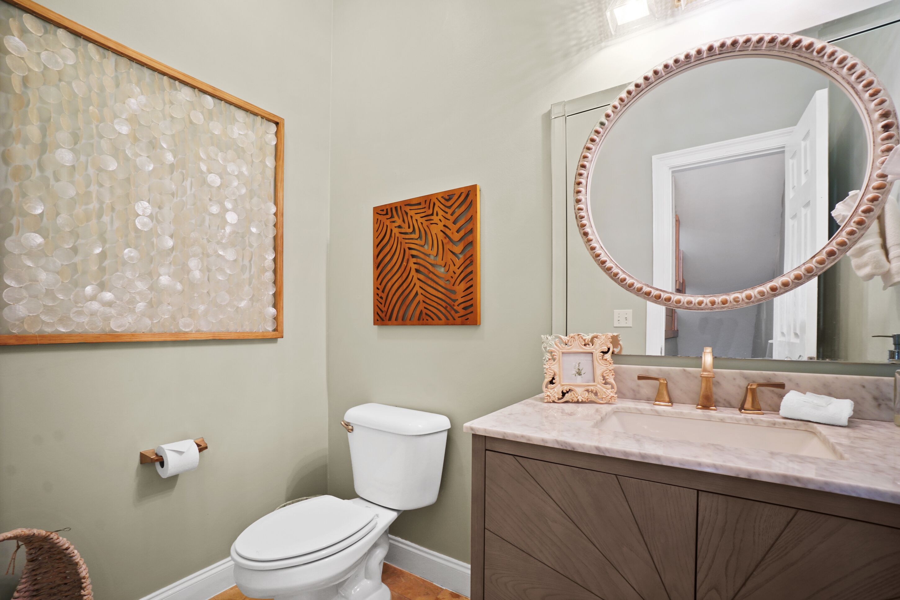 Un baño con inodoro, lavamanos, espejo y decoración en la pared.