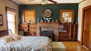 A bedroom with a bed, a ceiling fan, a fireplace, and bookshelves. - This big old charming house Viroqua (Viroqua)