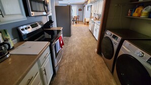A compact kitchen with a stove, oven, microwave, and a washing machine. - This big old charming house Viroqua (Viroqua)
