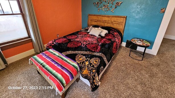 Ein Schlafzimmer mit Bett, einer Bank, einem kleinen Tisch und einer Wanddekoration.