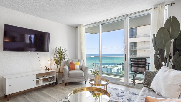 A modern living room with a flat-screen TV, a sofa, a coffee table, and a balcony with a view of the ocean. - Stunning ocean front unit 2/2 with privet beach excess (Hollywood)