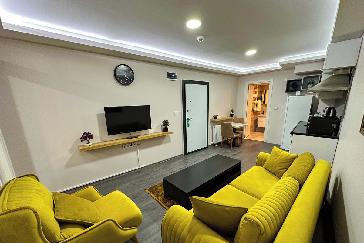 A modern living room with a sofa, a coffee table, a TV, and a dining area.
