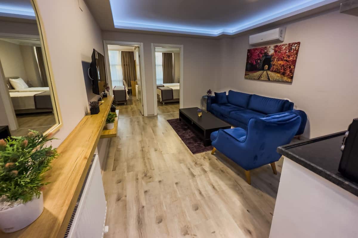 Un salon moderne avec un canapé bleu, une table basse en bois et un grand miroir. On aperçoit une petite plante sur la table basse et un tableau au mur.