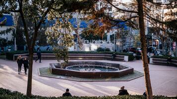 A public square with a central fountain, benches, and trees.