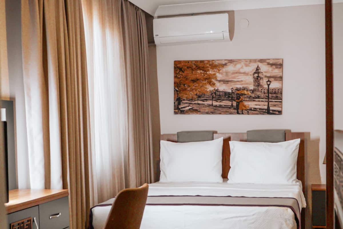 Une chambre d’hôtel équipée d’un lit, d’une chaise, d’un bureau et d’un appareil de climatisation.