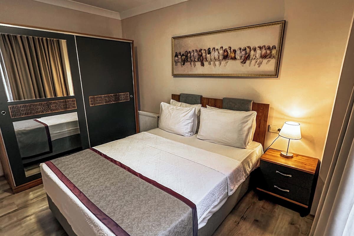 Une chambre à coucher comprenant un lit, une table de chevet, une commode, une armoire et un tableau accroché au mur.