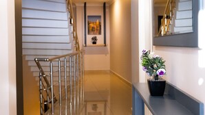 Un pasillo moderno con una escalera, una planta en maceta y un espejo en la pared.