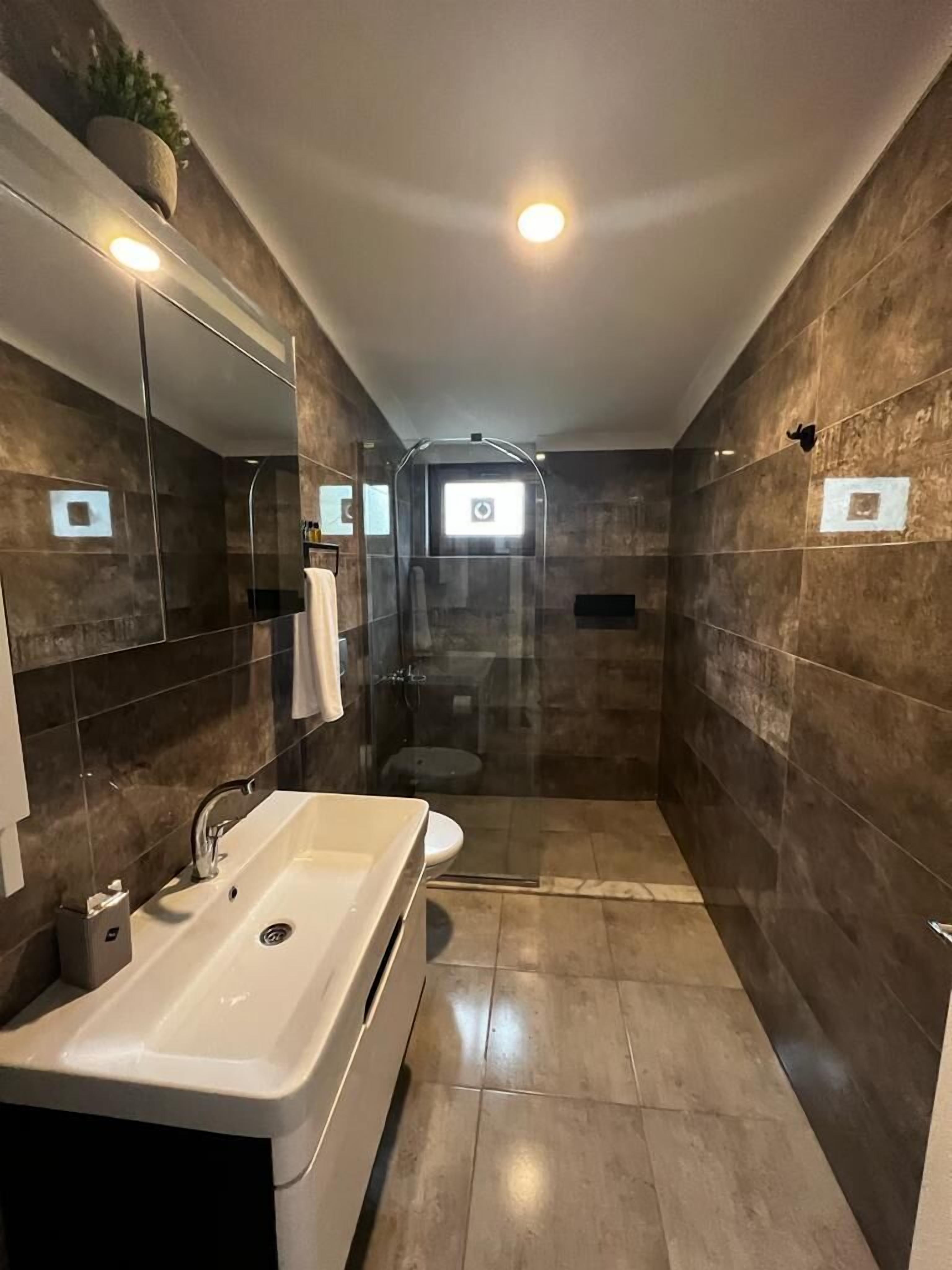 Ein modernes Badezimmer mit einem großen Waschbecken, einer Duschkabine und einer Toilette.