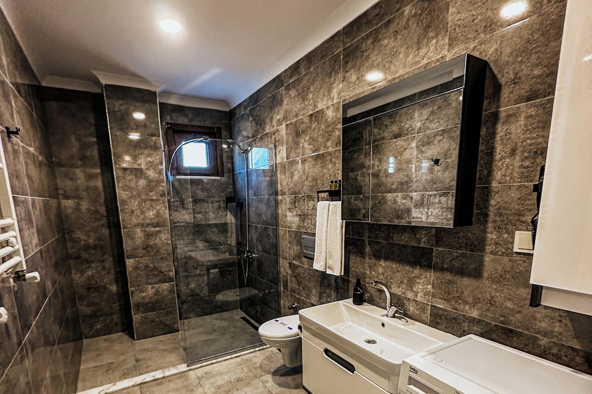 Un baño moderno con cabina de ducha, inodoro, lavabo y lavadora.