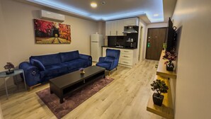 Un espacio habitable pequeño con sofá, mesa de centro y una zona de kitchenette.