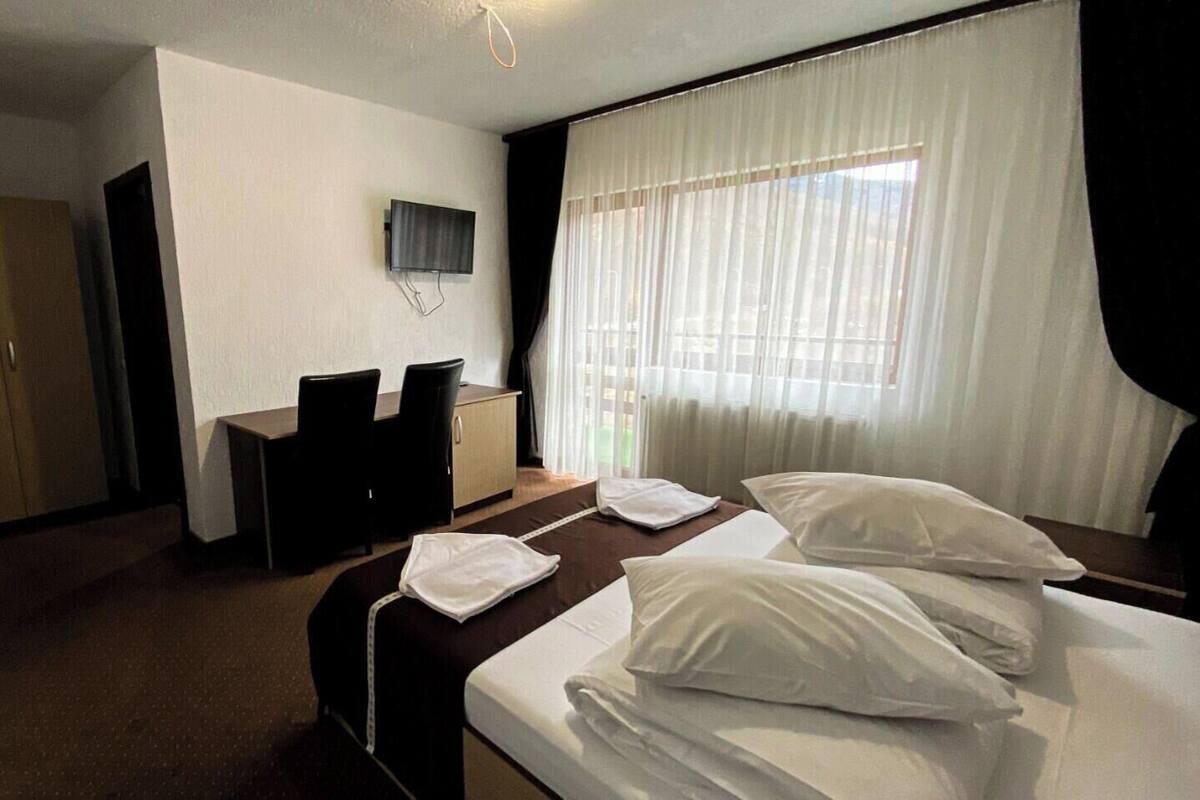 A hotel room with a bed, a desk, a television, and a wardrobe.