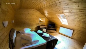 A cozy, wooden cabin bedroom with a bed, a dresser, a TV, and a skylight. - Hanul Patrisiei (Cartisoara)