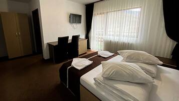 Una habitación de hotel con cama, escritorio, silla, televisión y armario.