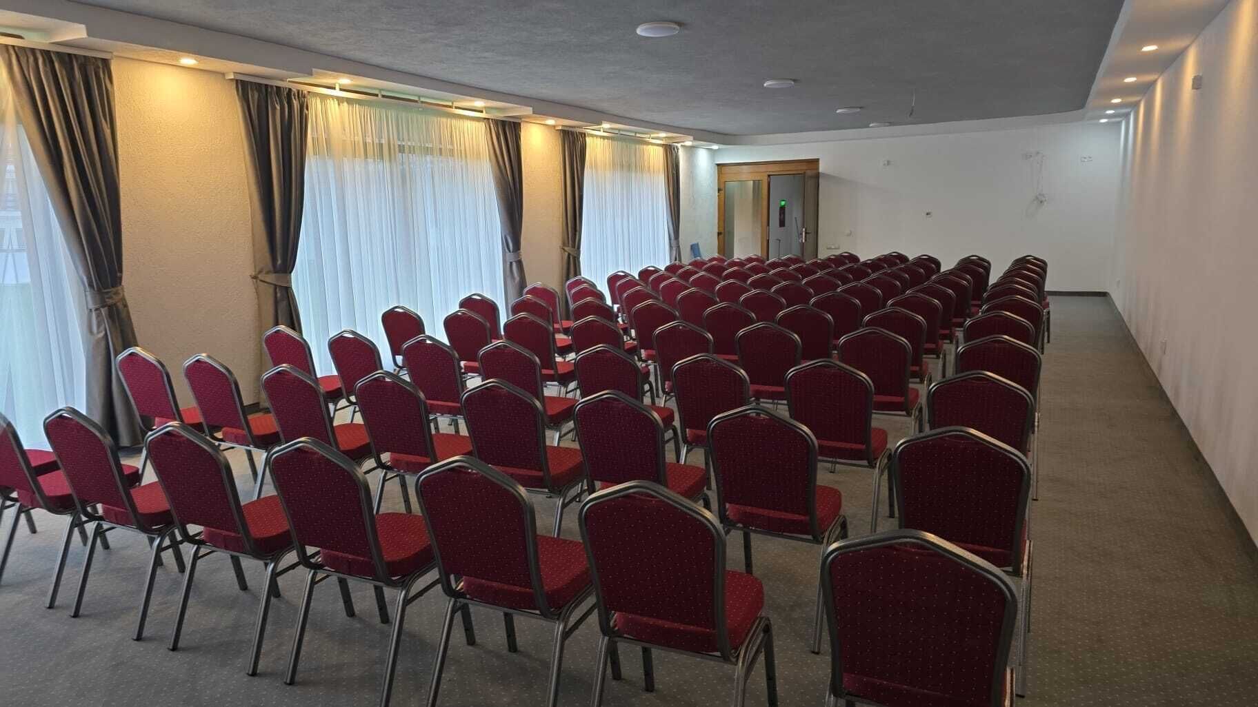 A conference room with rows of red chairs and a carpeted floor.