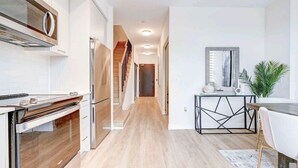 Una cuina moderna amb electrodomèstics d'acer inoxidable, un taulell de fusta i una escala que puja a un altre pis.