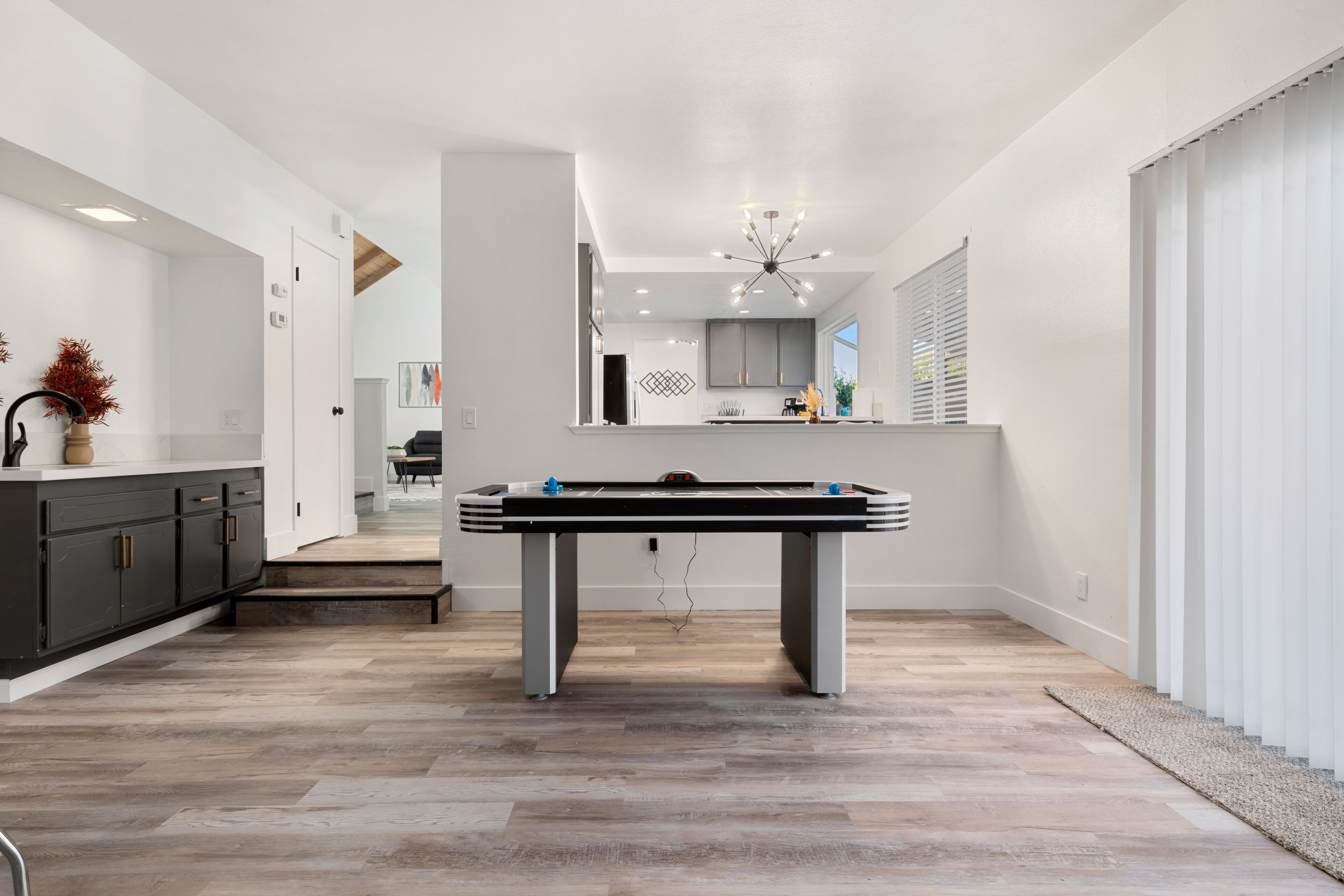 Een moderne keuken met een pooltafel, houten vloeren en een kroonluchter.