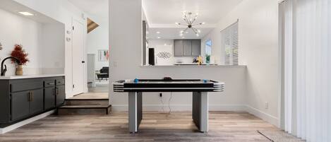 Een moderne keuken met een pooltafel, houten vloeren en een kroonluchter.