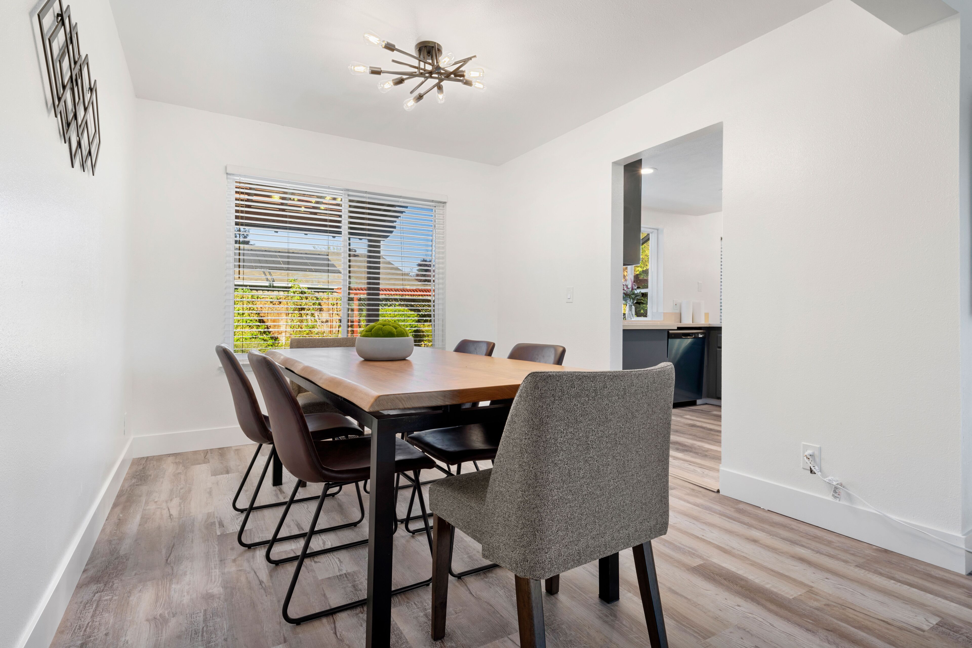A modern dining room with a wooden table, six chairs, and a ceiling light fixture.