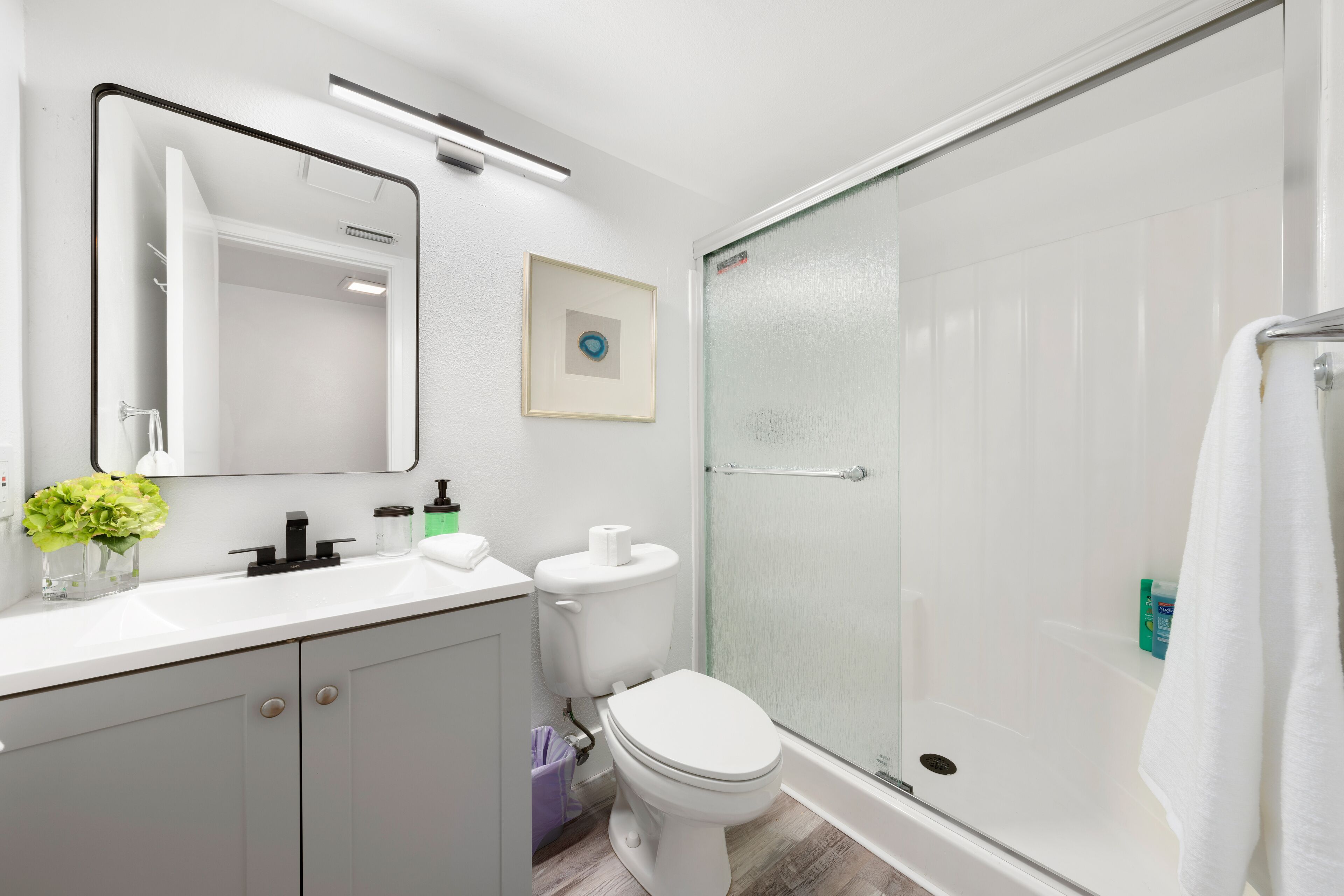 Een moderne badkamer met een wit wastafelmeubel, toilet en een douchecabine met glazen wanden.