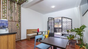 Un comedor con un banco de madera, sillas azules y amarillas, una mesa y un dispensador de agua.
