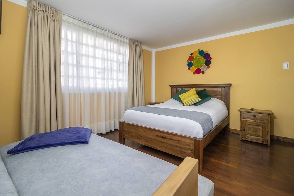A bedroom with a bed, a nightstand, a window with curtains, and a wall decoration.