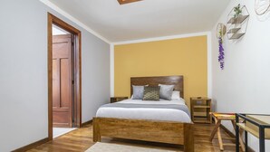 Un dormitorio con una cama de madera, una mesita de noche y un escritorio pequeño con una silla.