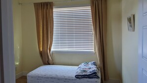 A small bedroom with a single bed, beige curtains, and a window with blinds. - Family home at Rohnert Park (Rohnert Park)