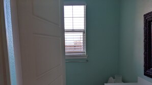 A small bathroom with a toilet, sink, and window. - Family home at Rohnert Park (Rohnert Park)