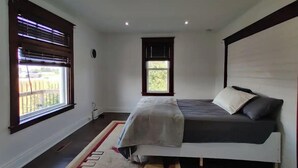 Une chambre à coucher avec un lit, deux fenêtres, un luminaire au plafond et une petite fenêtre.